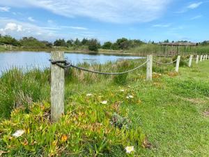 a wooden post with a rope on a fence next to a lake at ECO Lodge Villa Villekula in The Crags