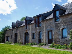 une grande maison en pierre avec une pelouse verte dans l'établissement Domaine De Kerstinec/Kerland, à Riec-sur-Bélon