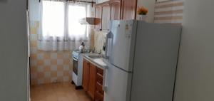 uma cozinha com um frigorífico branco e um lavatório em Flomar em Piriápolis