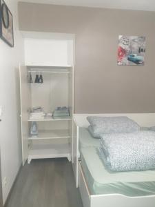 a white bedroom with a bed and a shelf at studio meublé au RDC , proche lac in Aix-les-Bains