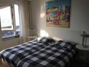 1 dormitorio con 1 cama con manta a cuadros en Strandhuis, en Egmond aan Zee