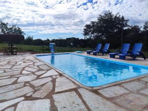 a swimming pool with blue lounge chairs in a yard at Quinta do Vale in Pirenópolis
