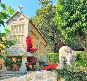 a small house with red flowers in a garden at Casa Turistica Nigrán in Nigrán