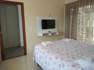 a bedroom with a bed and a tv on the wall at Residence Vila Europa in Porto Seguro