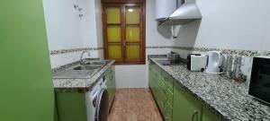 a kitchen with green and white counters and a sink at Casa Puerta de la Victoria in Córdoba