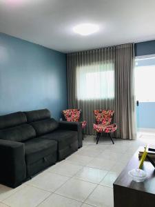 a living room with a black couch and two chairs at Aconchego na Capital do Forró in Caruaru
