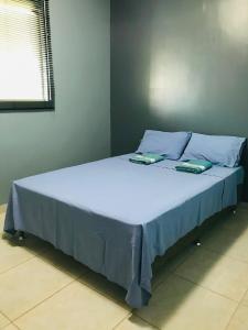 a large bed with blue sheets and pillows at Aconchego na Capital do Forró in Caruaru