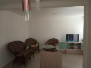 a living room with chairs and a table and a tv at Duplex Paraíba Litoral Sul Jacumã Acesso as Melhores Praias do Brasil in Jacumã