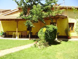 una casa amarilla con una mesa y un banco en el patio en El Porma en Villanueva del Condado