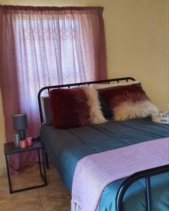a bed with two pillows on it with a window at Rhumbini Lodge in Malamulele