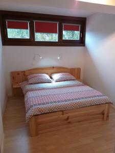 a bed in a small room with two windows at Apartment Pri Vrtnici in Šmartno ob Paki