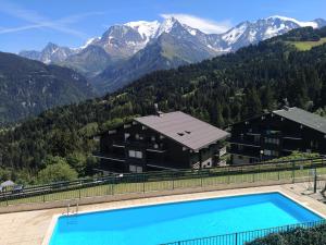 un complexe avec une piscine et des montagnes en arrière-plan dans l'établissement appart st gervais le Topaze, à Saint-Gervais-les-Bains