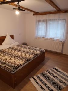 a bedroom with a bed and a window and two rugs at Casa Livada Bunicii in Tîrgu Ocna