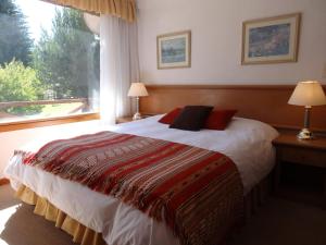 a bedroom with a bed with a large window at Hotel Punta Condor in San Carlos de Bariloche