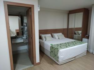 ペドラ・アズールにあるApartamento em Pedra Azul, Condomínio Vista Azulのベッドルーム1室(ベッド1台付)、バスルーム(鏡付)