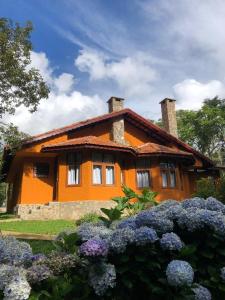 une maison orange avec des fleurs devant elle dans l'établissement Pousada Opas Haus, à Camanducaia