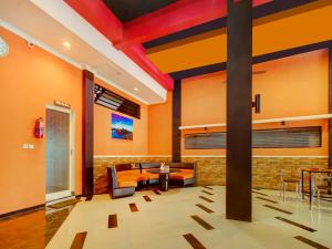 a lobby with orange walls and a table and chairs at Super Capital O 90151 Guest House 180 in Batu