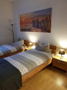 two beds in a room with two lamps and a painting at maria' s FeWo in Wallerfangen