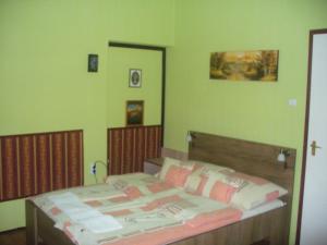 1 dormitorio con 1 cama con paredes verdes en Pleiveisz Apartman, en Sárvár