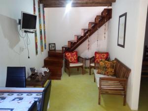 a living room with stairs and chairs and a tv at Pousada Grafite in Trancoso