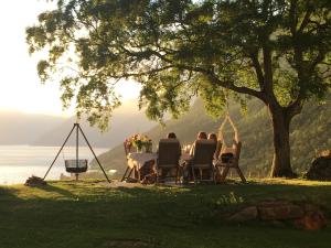 een groep mensen die aan een tafel onder een boom zitten bij Huse Gjestegard in Kinsarvik