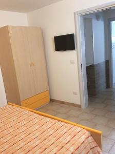 une chambre avec un lit et une télévision au mur dans l'établissement Appartamenti STELLA MARINA- Posto Rosso, à Alliste
