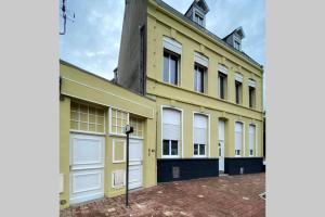 un edificio amarillo con puertas blancas de garaje en La Maison Sévigné - Appart Hôtel - N°6 L'indus, en Béthune