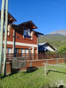 a brick house with a fence in front of it at ROCA AZUL in El Bolsón