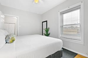 a white bedroom with a large bed and a window at 1BR Apartment in Rogers Park with King Bed - Lunt 2E in Chicago