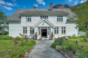 a white house with flowers in the front yard at Huse Gjestegard in Kinsarvik