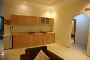 a kitchen with wooden cabinets and a couch at Ghasaq Al Leil Aparthotel in Taif