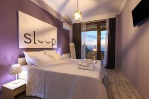 een slaapkamer met een groot wit bed en een raam bij View and the city in Thessaloniki