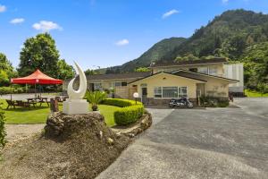 a house with a statue in front of a driveway at Te Aroha Motel in Te Aroha
