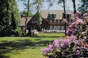 a large house in a yard with pink flowers at Heidehotel Waldhütte in Telgte