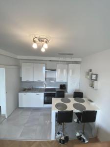 cocina con armarios blancos, mesa y sillas en Apartment Lilly, en Rijeka