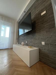 sala de estar con TV en una pared de ladrillo en Apartment Lilly, en Rijeka