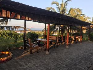 a picnic shelter with benches and a view of the ocean at beach front stephen's house in Inchaban