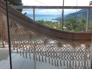 a hammock in a room with a view of the ocean at Linda casa com vista pro mar!! in Ilhabela