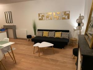 a living room with a black couch and tables at chez Muriel,T2 de charme, parc Ste Marie, Nancy Thermal, Mon Désert in Nancy