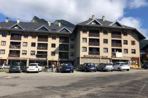 un gran edificio con coches estacionados en un estacionamiento en Residence les bleuets en Saint-Pierre-de-Chartreuse