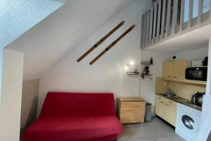 a living room with a red couch and a kitchen at Residence les bleuets in Saint-Pierre-de-Chartreuse