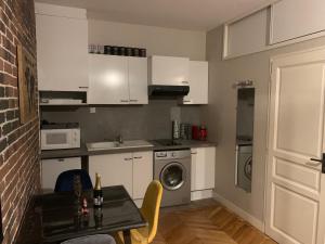 una pequeña cocina con armarios blancos y una mesa con comedor. en Appartement centre Fontainebleau, en Fontainebleau