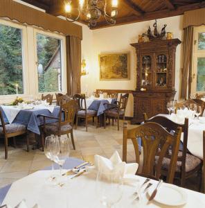 a restaurant with tables and chairs with white tablecloths at Heidehotel Waldhütte in Telgte