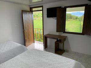 a bedroom with two beds and a television and a window at Finca El Bazar in Montenegro