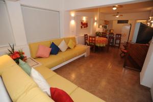 a living room with a yellow couch with colorful pillows at La Ceiba del Mar in Zihuatanejo
