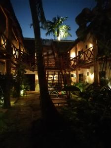 a building with stairs and a palm tree at night at Kin Ha Tulum Hotel in Tulum