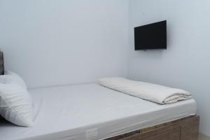 a bed with white sheets and a tv on top at hotel padma tangerang in Tangerang