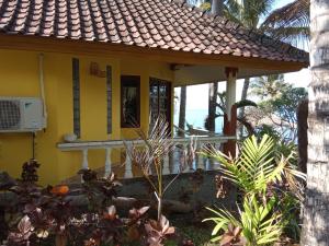 una casa amarilla con un porche con el océano en el fondo en Villa Arjuna en Seraya