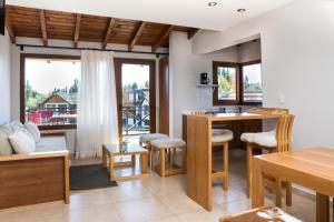 a living room with a table and chairs and a balcony at Encanto sobre el Nahuel in Dina Huapi