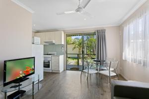 een woonkamer met een televisie en een tafel en stoelen bij Murray River Holiday Park in Moama